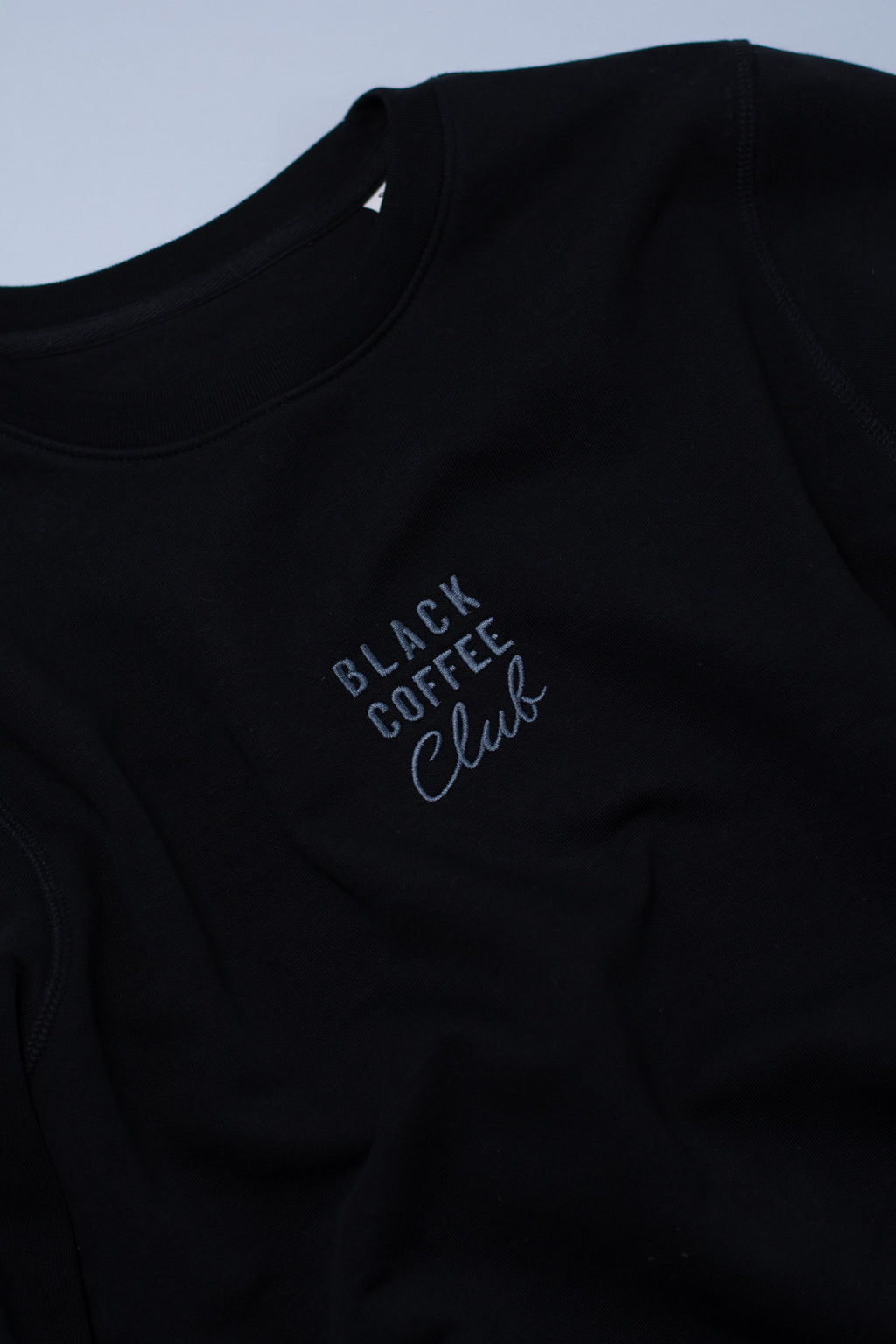 Black sweatshirt with 'Black Coffee Club' text on a light blue background