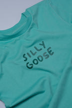 Teal t-shirt with 'SILLY GOOSE' text on a light gray background