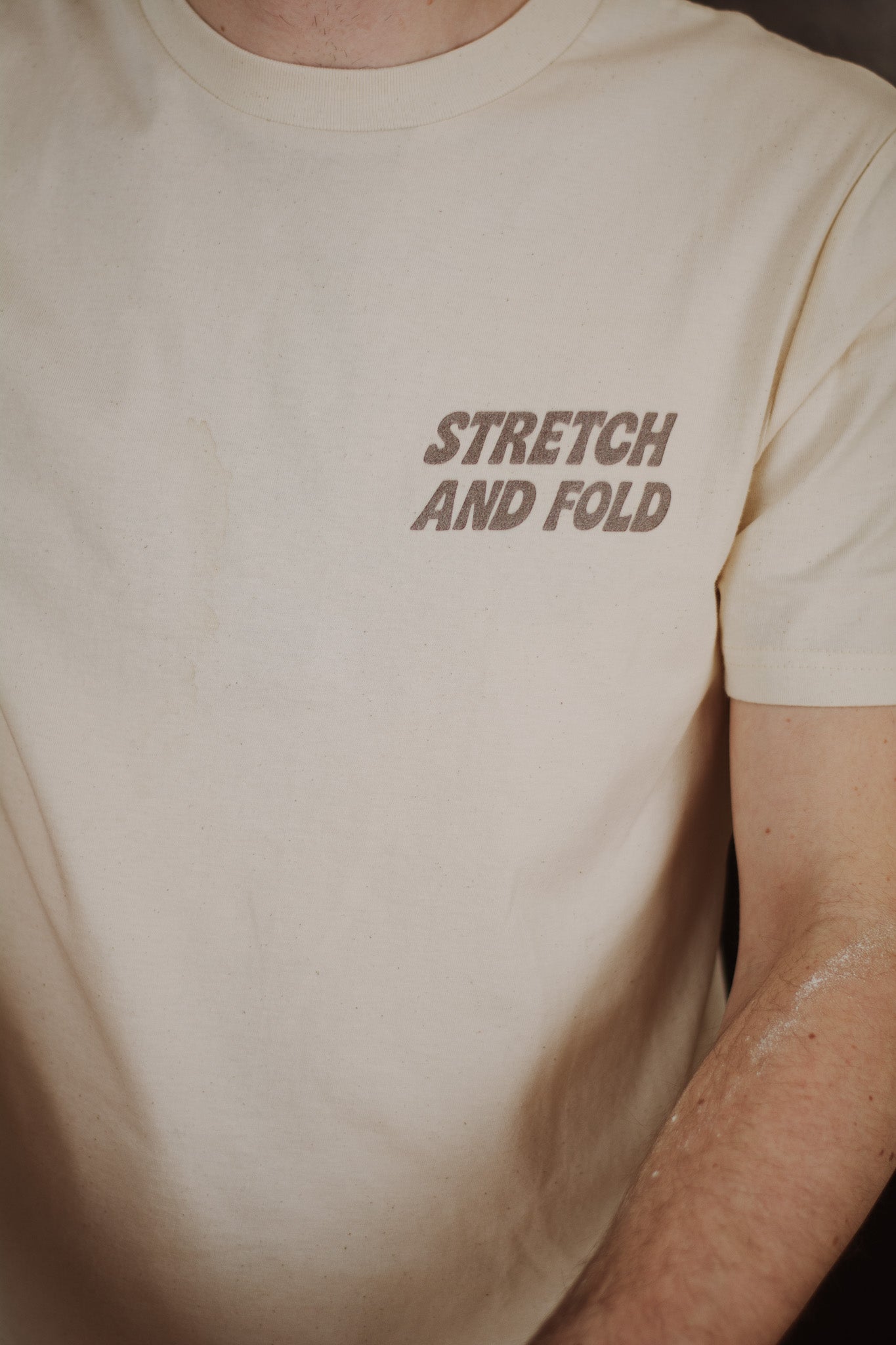 Beige t-shirt with 'STRETCH AND FOLD' text on a plain background