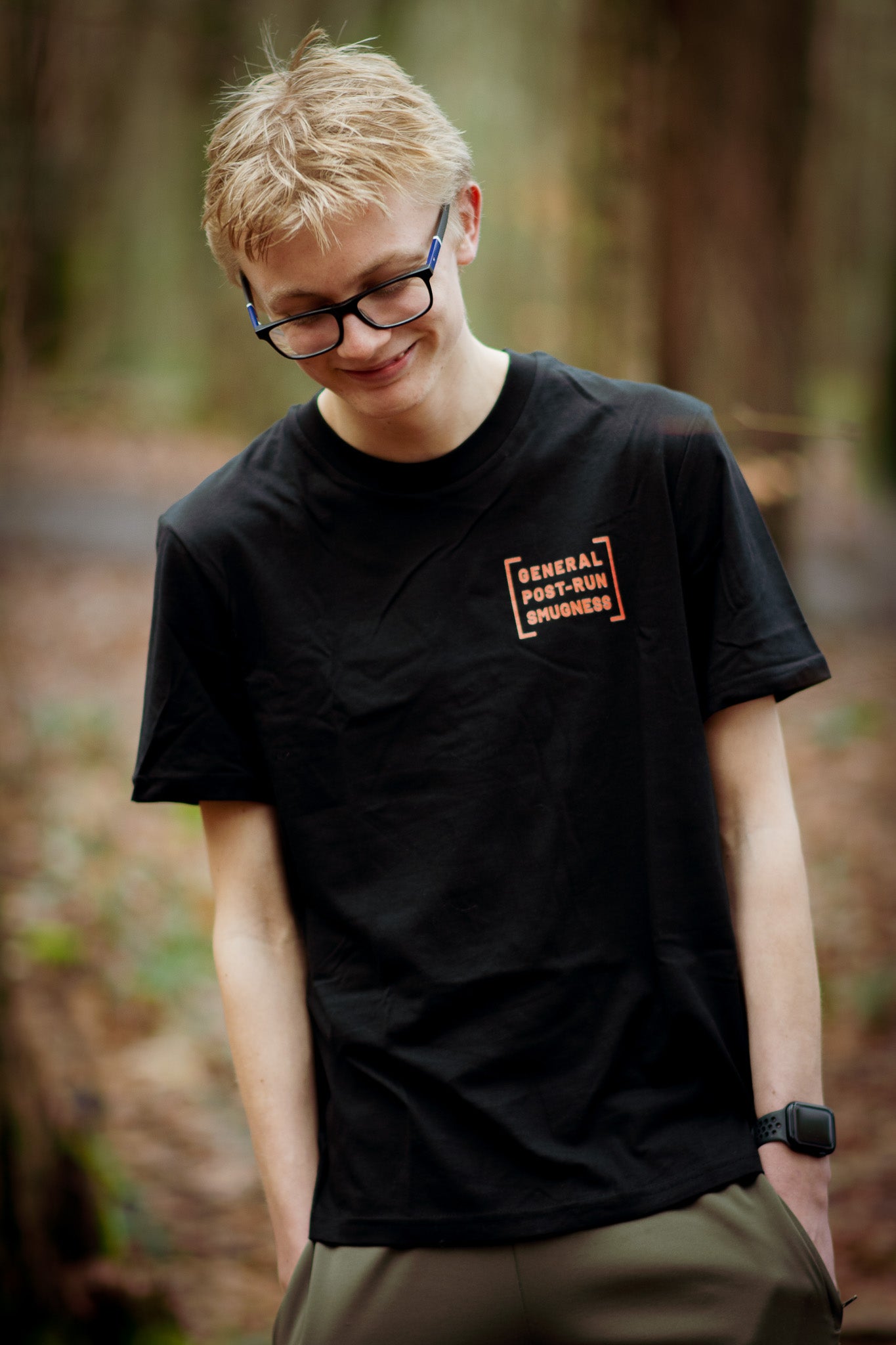 Person wearing a black t-shirt with text in a forest setting