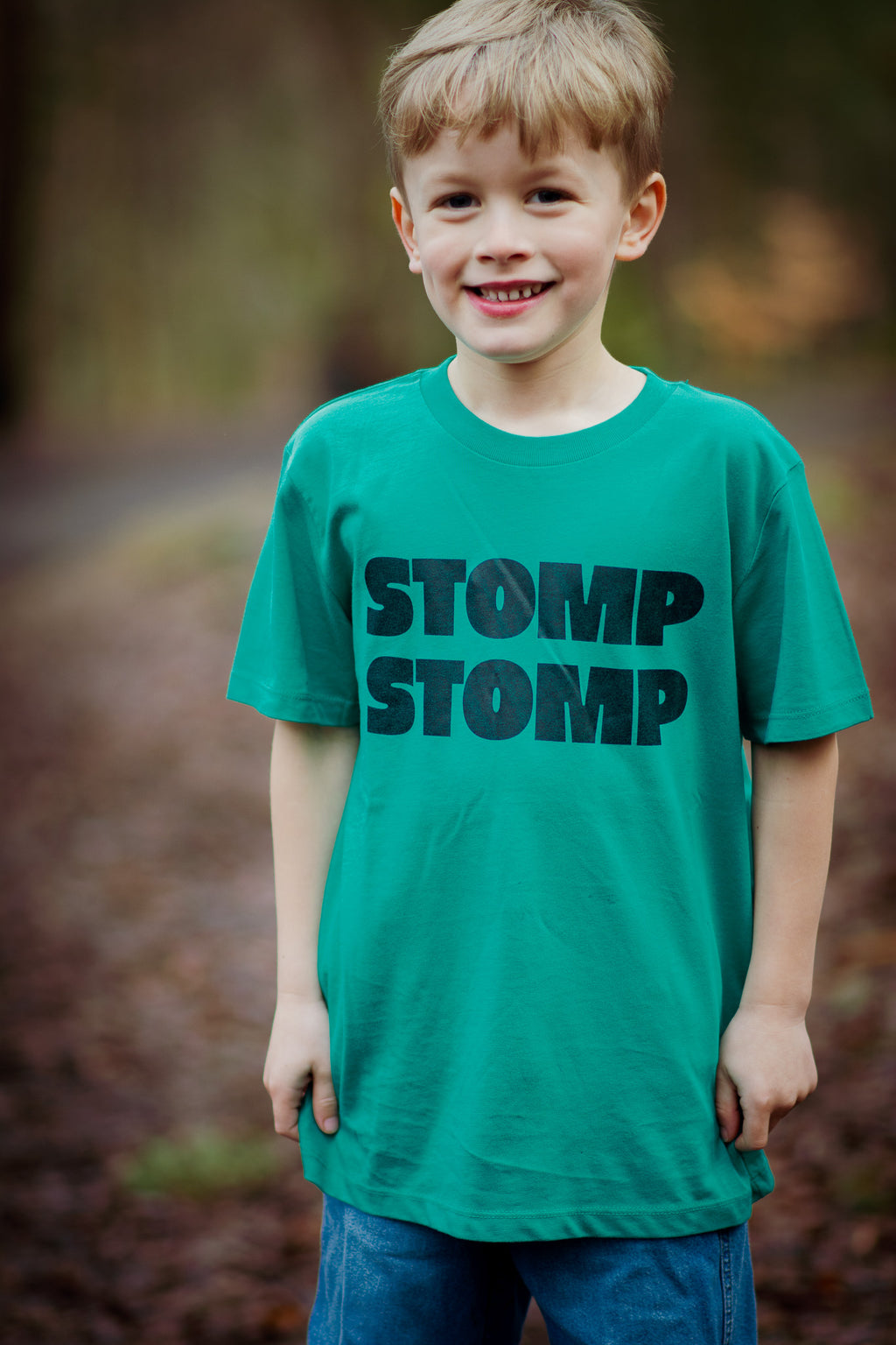 Child wearing a green t-shirt with 'STOMP STOMP' text outdoors.