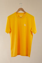 Yellow t-shirt with a small logo on a beige background