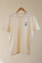 Beige t-shirt with a small blue logo on a wooden hanger against a beige background