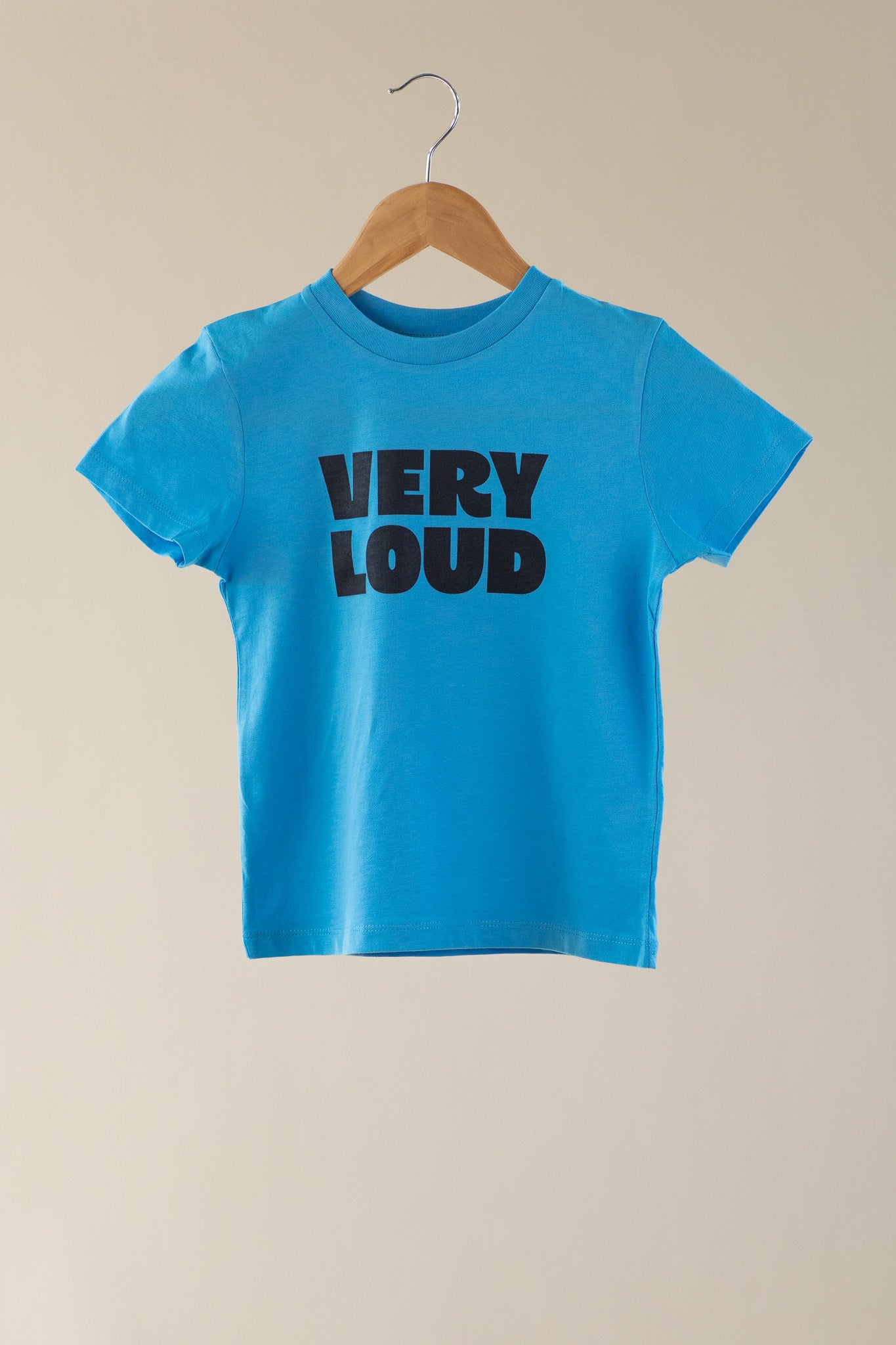 Blue t-shirt with 'VERY LOUD' text on a beige background