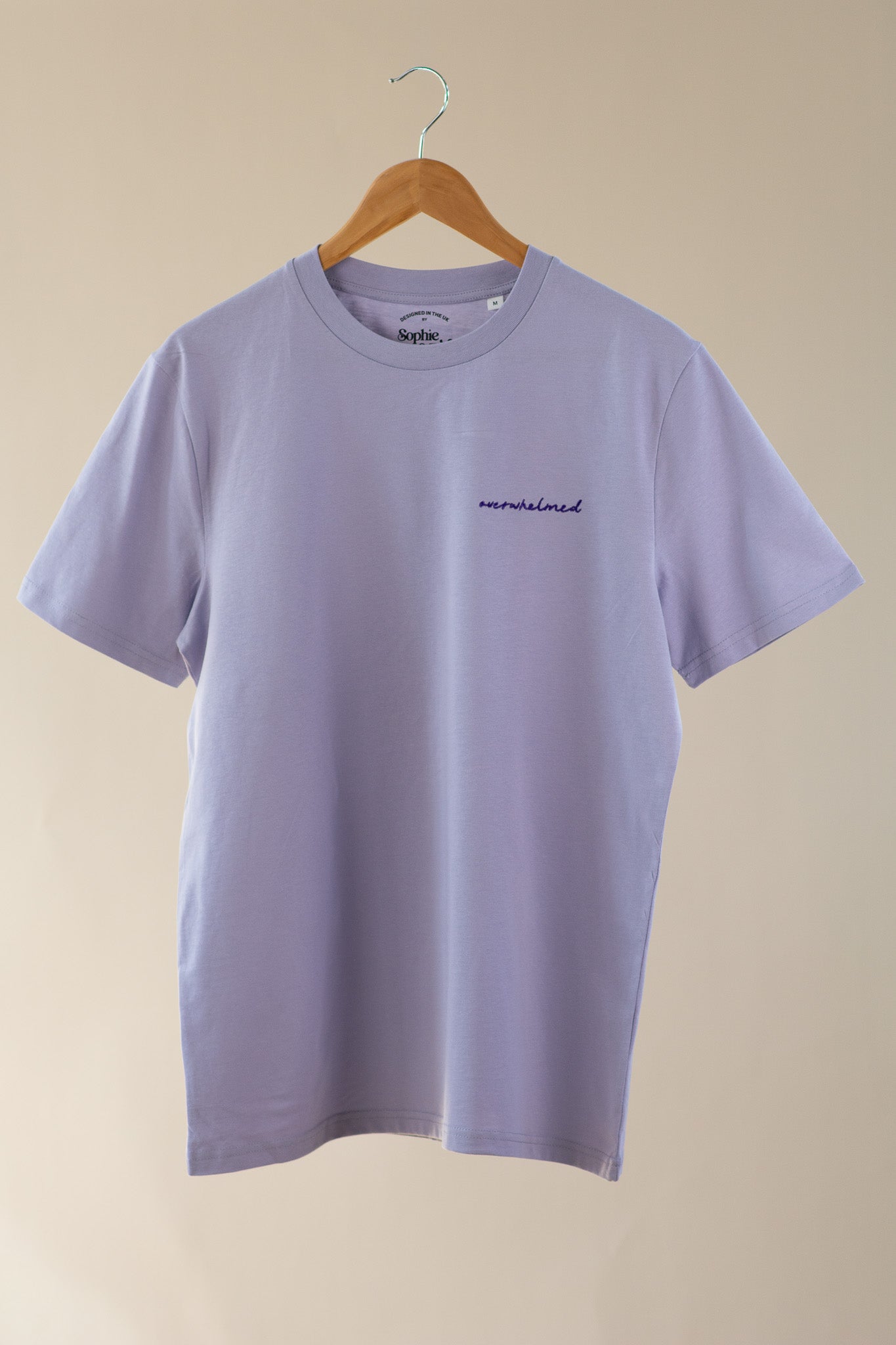 Purple t-shirt with a small logo on a beige background