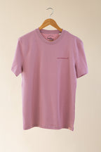 Pink t-shirt with text on a hanger against a beige background