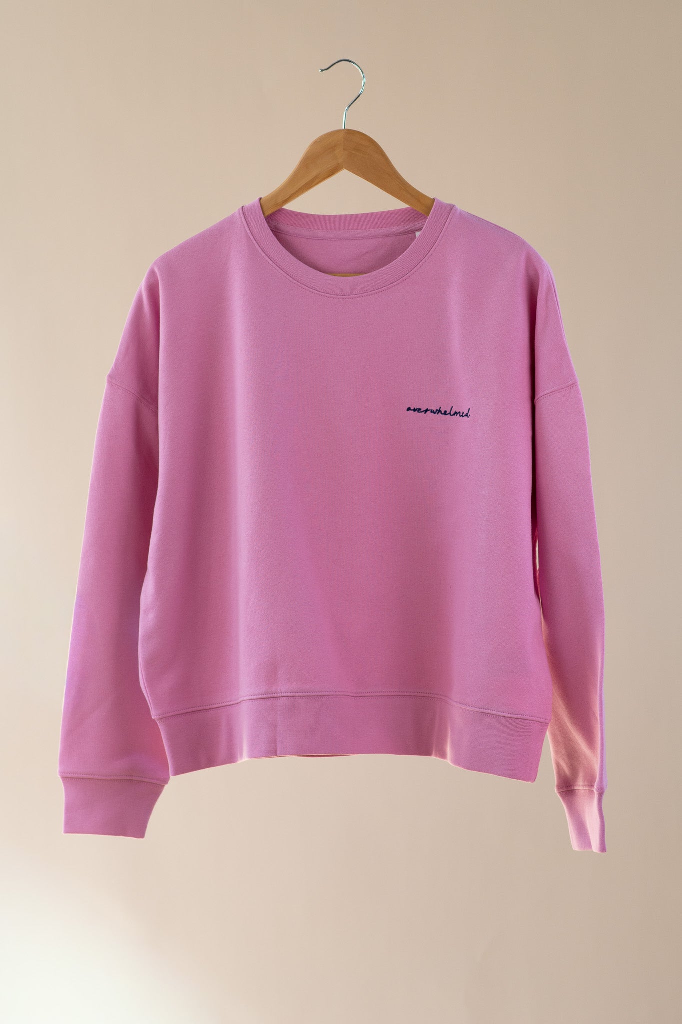 Pink sweatshirt with text on a beige background