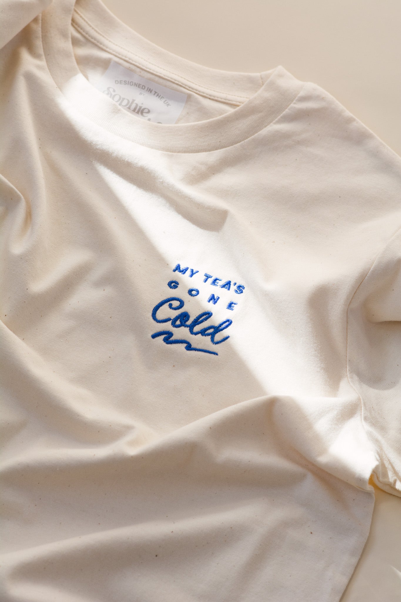 White t-shirt with blue text 'My tea's gone cold' on a light background