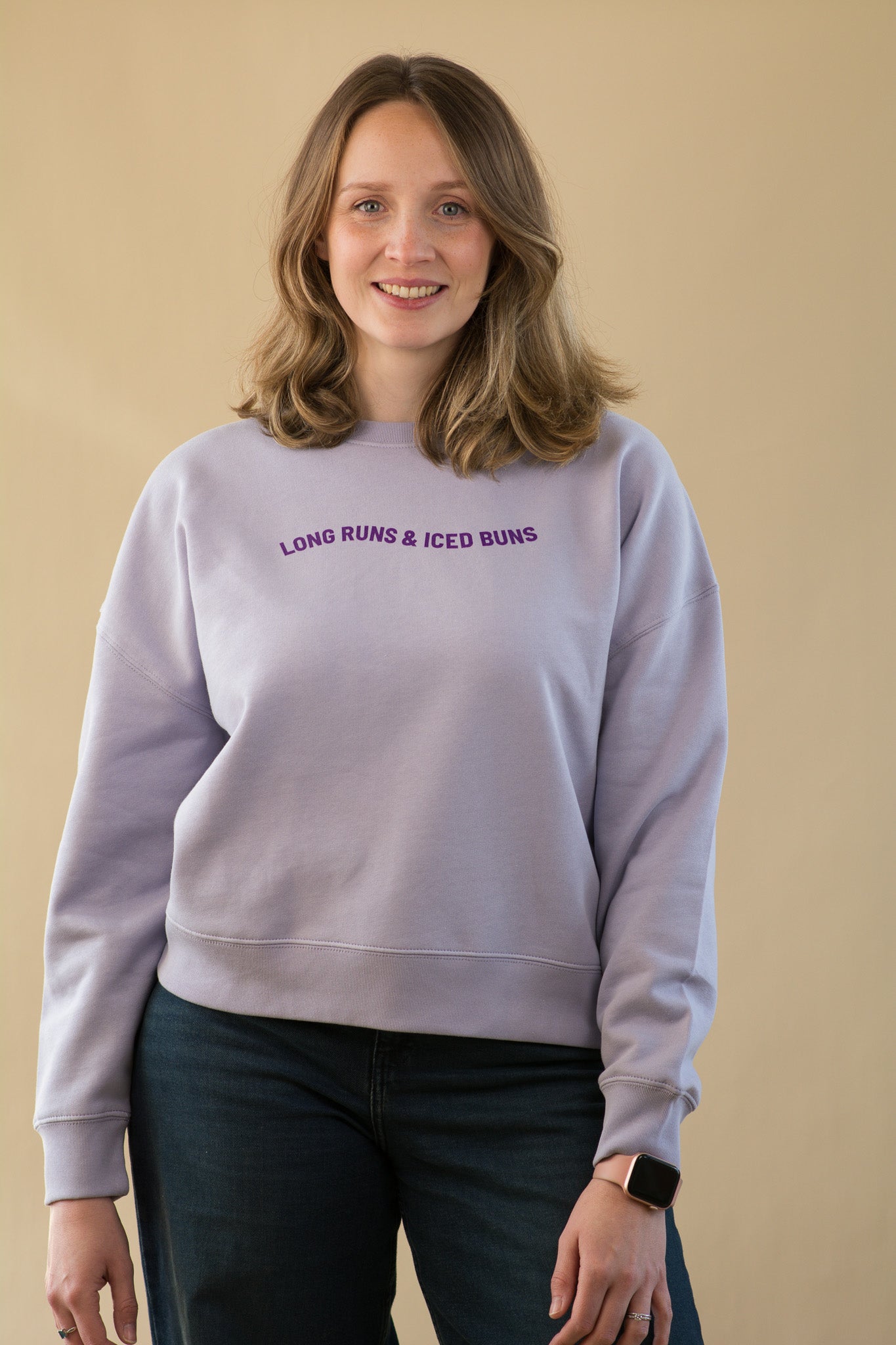 Woman wearing a light purple sweatshirt with text on a beige background