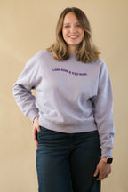 Woman wearing a light gray sweatshirt with text on a beige background