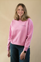 Person wearing a pink sweatshirt with text on a beige background