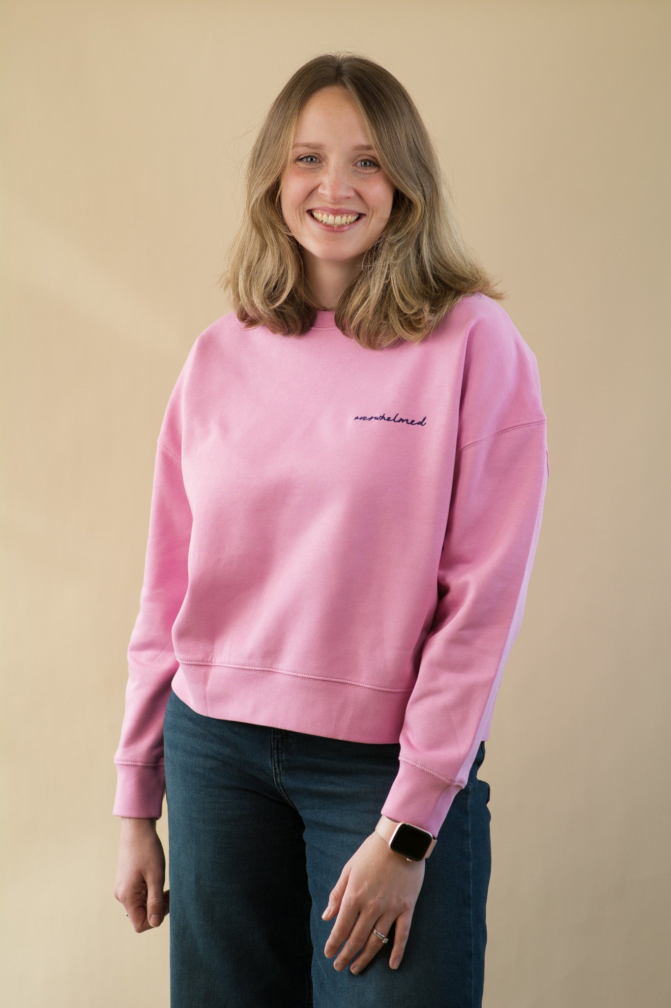 Person wearing a pink sweatshirt with text on a beige background