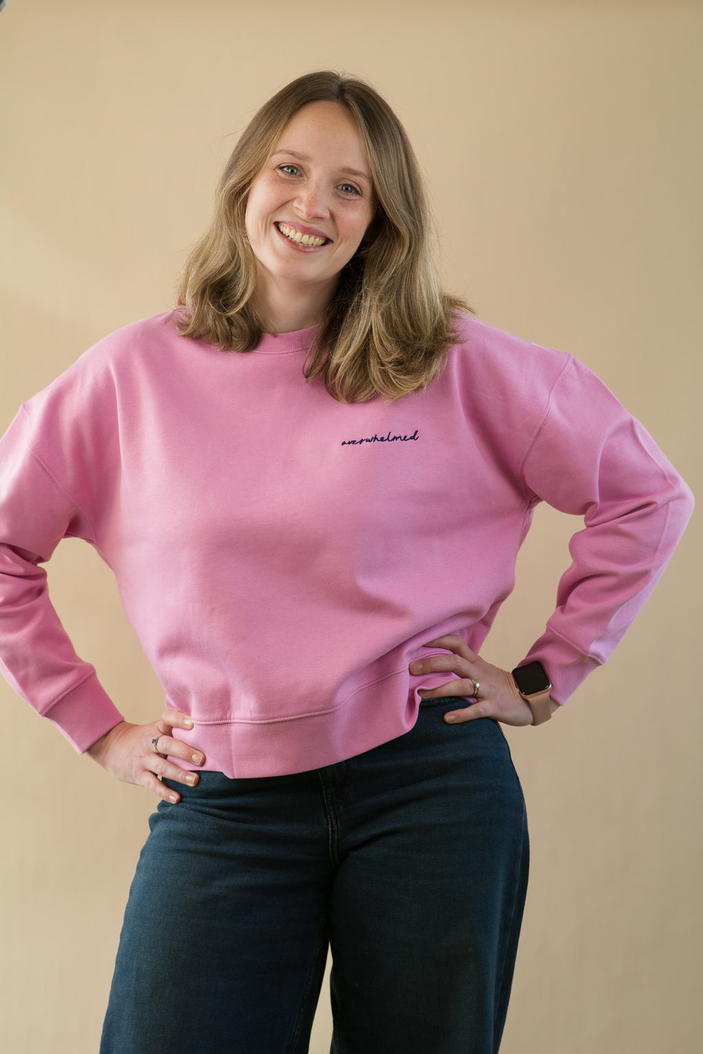 Person wearing a pink sweatshirt with text on a beige background
