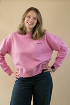 Person wearing a pink sweatshirt with text on a beige background