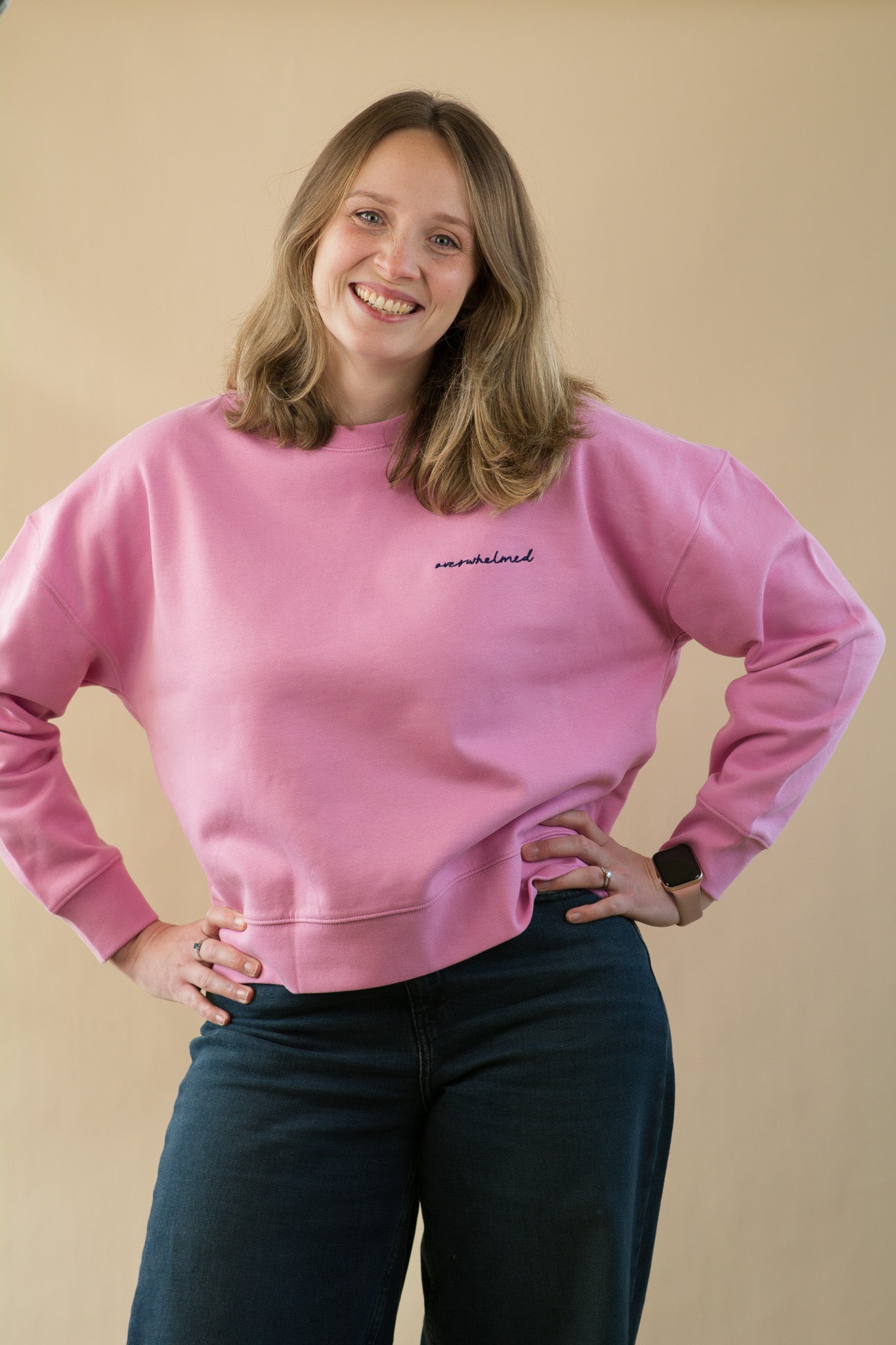 Person wearing a pink sweatshirt with text on a beige background