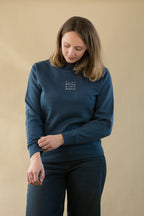 Woman wearing a blue sweater with text on a beige background