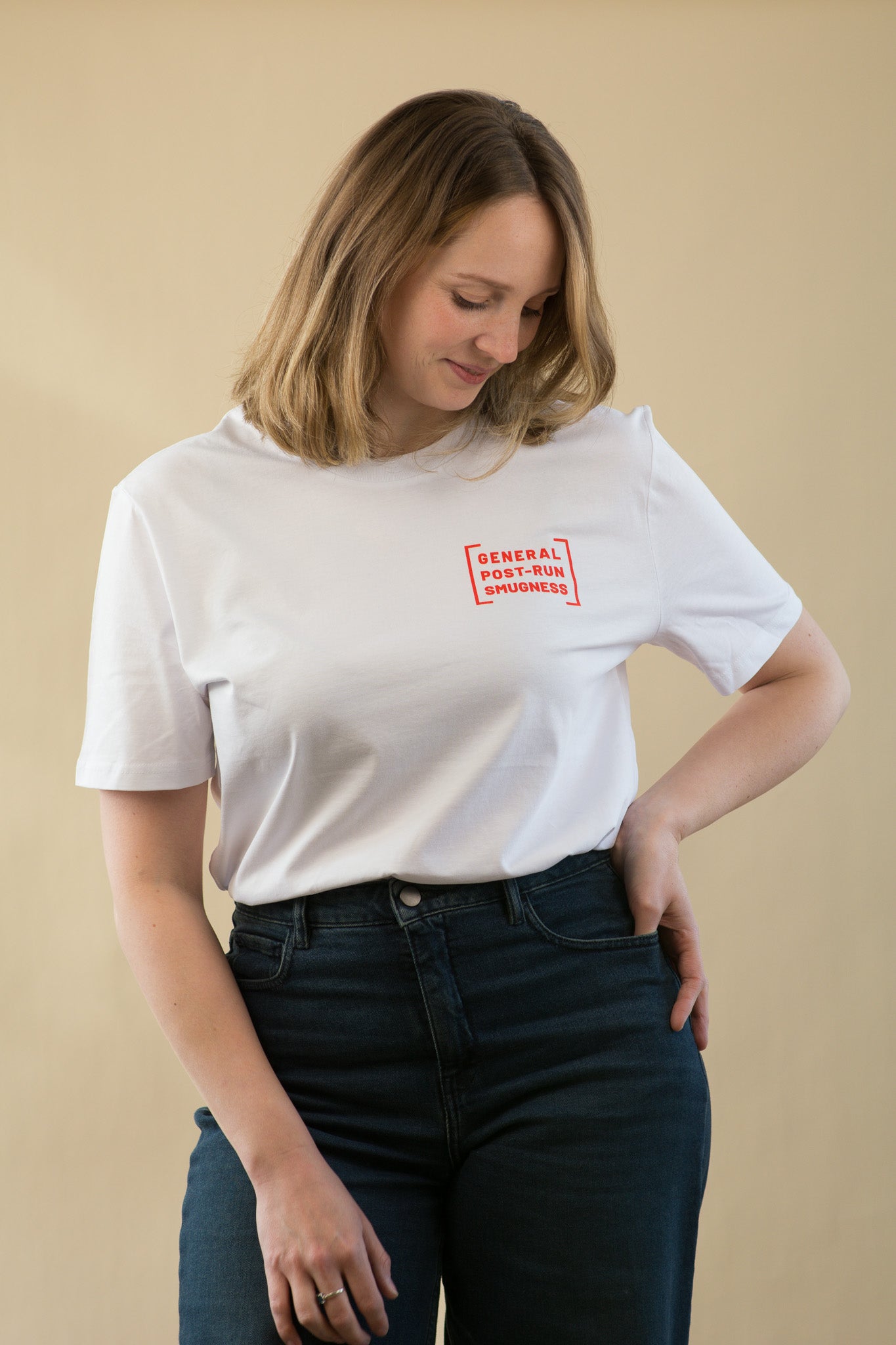 Woman wearing a white t-shirt with a red logo on a beige background