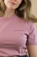 Woman wearing a pink t-shirt with text on a beige background