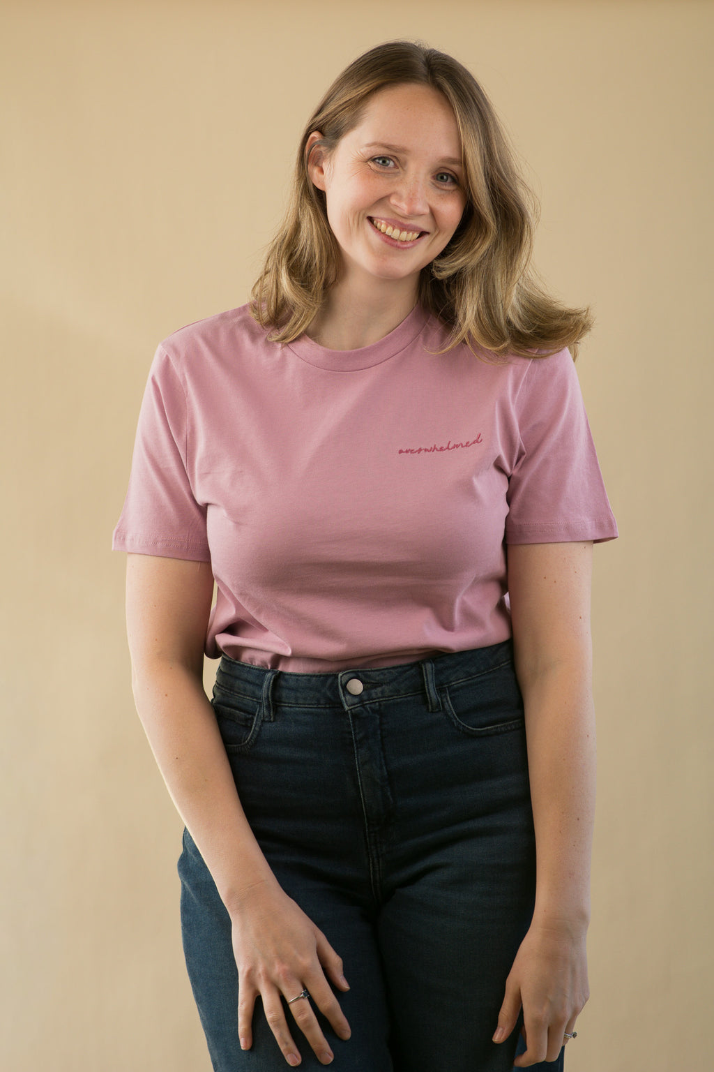 Woman wearing a pink t-shirt with text on a beige background