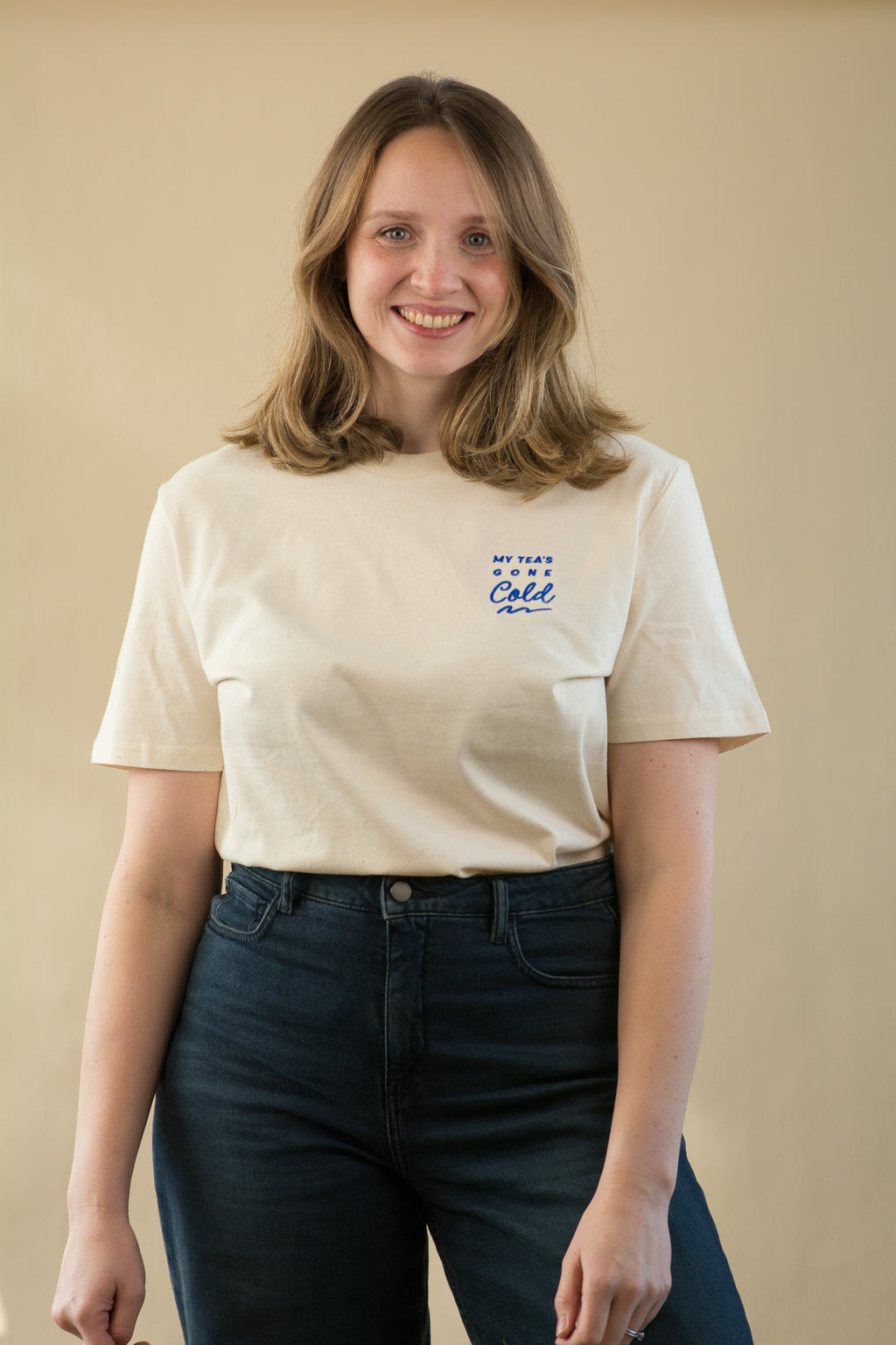 Woman wearing a white t-shirt with blue text against a beige background