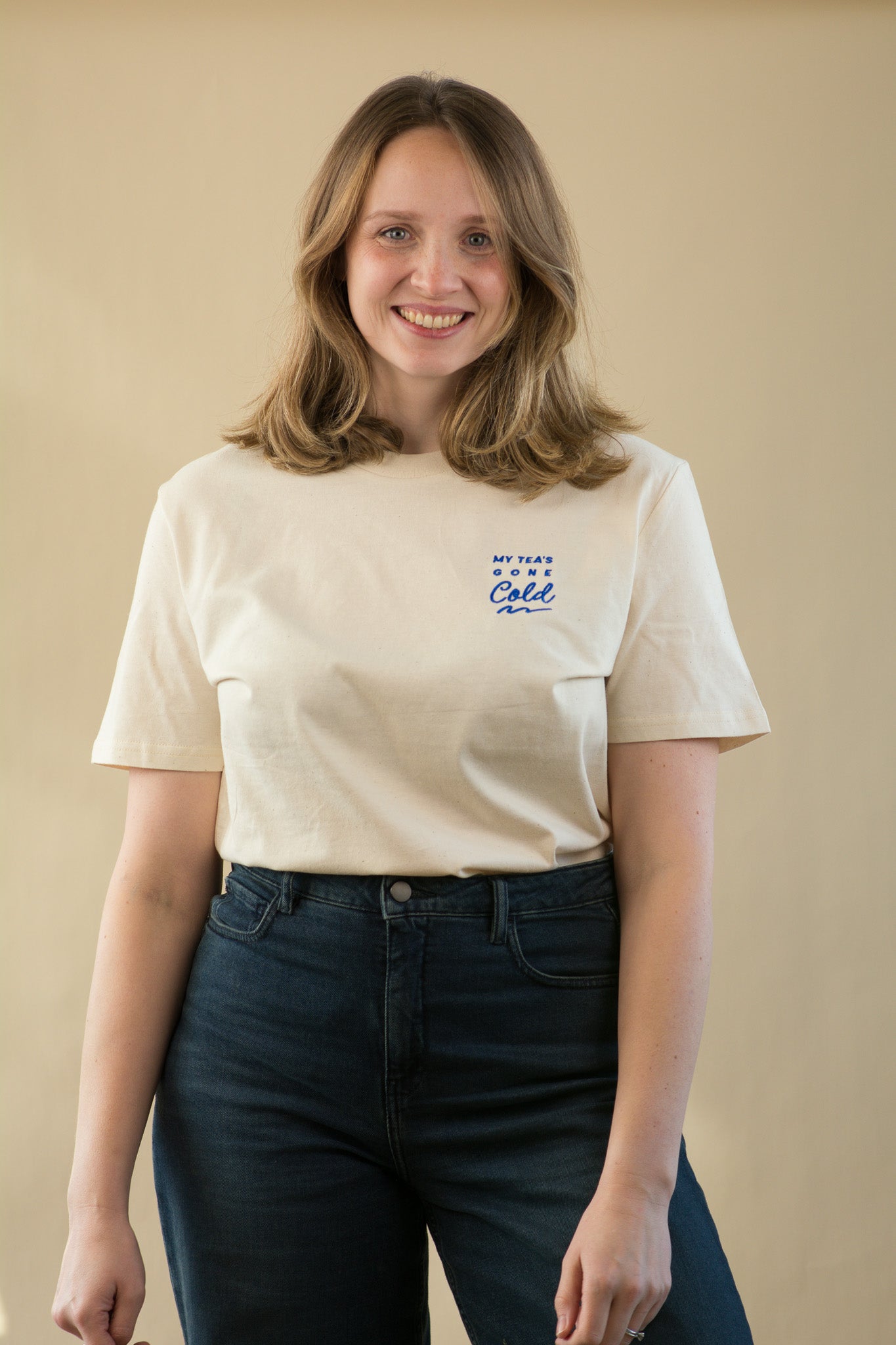 Woman wearing a white t-shirt with blue text against a beige background
