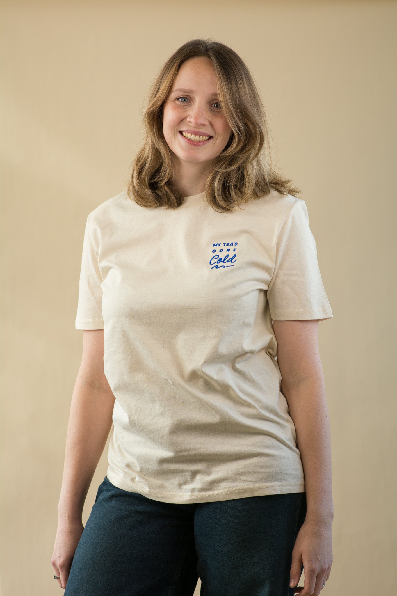 Woman wearing a beige t-shirt with text on a plain background