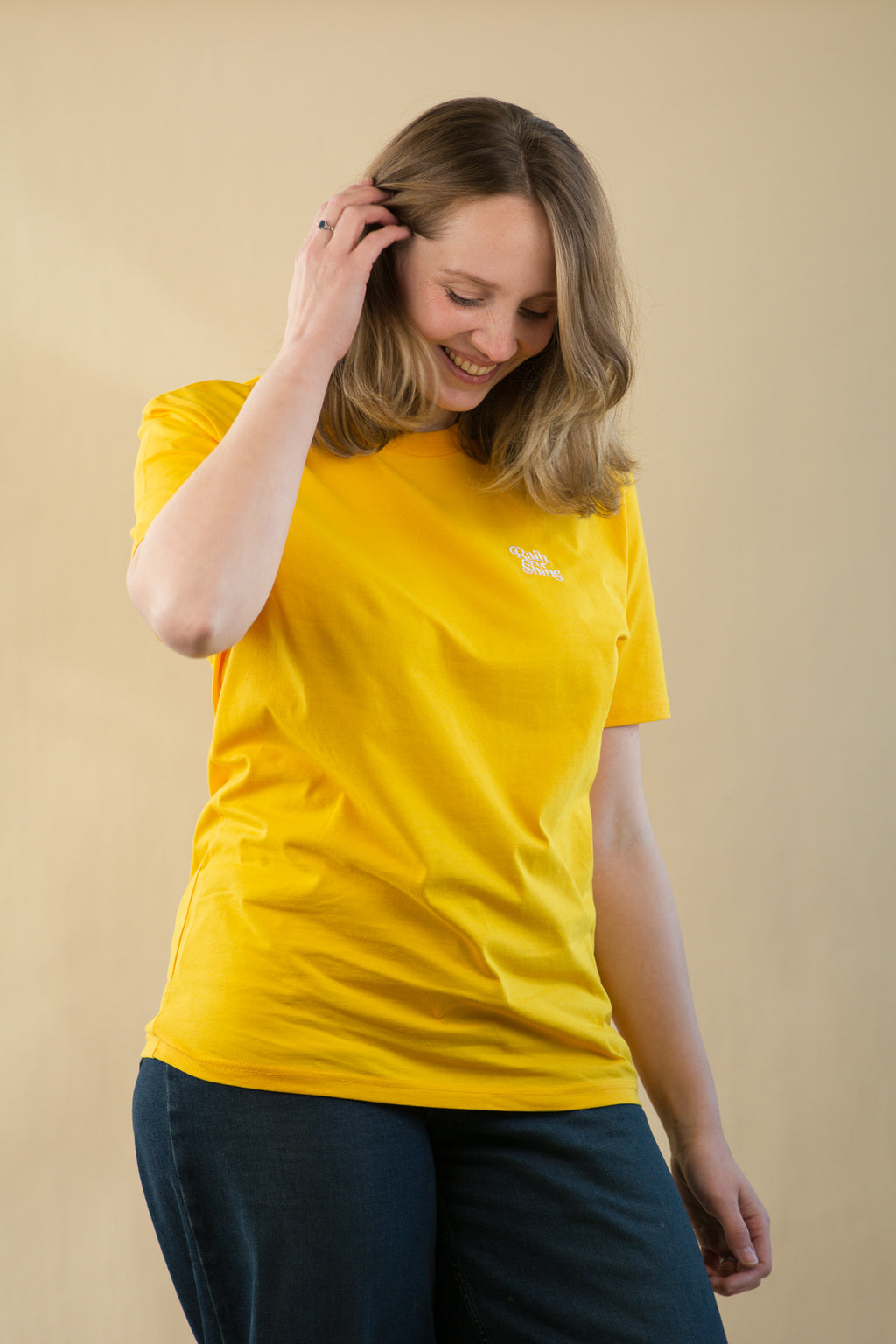 Woman wearing a yellow t-shirt with a logo on a beige background