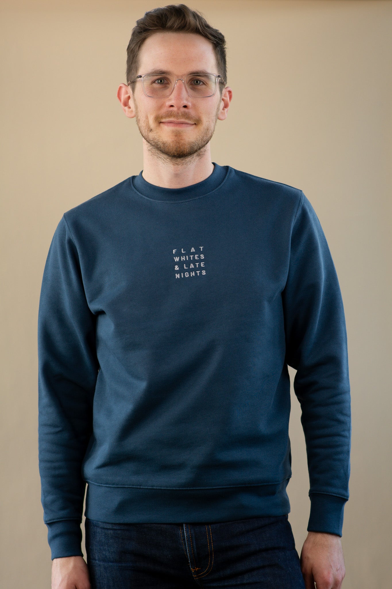 Man wearing a navy blue sweatshirt with text on a beige background